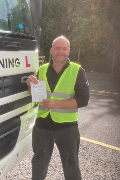 Man holding pass cerificate for HGV Driver Training Category C+E with PFS Training